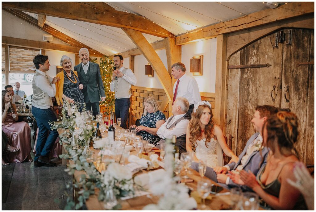 bride checking on groom during speeches at Cripps barn wedding