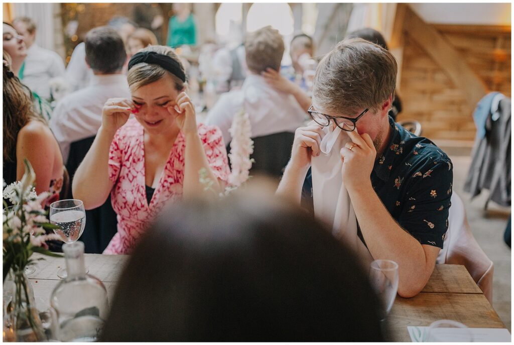 guests wiping away tears with a napkin under glasses at Cripps Barn wedding