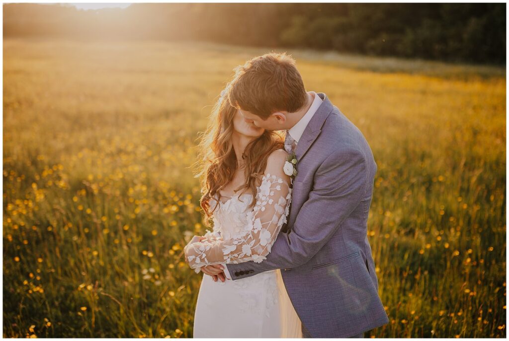 bride and groom kissing in the golden light of a yellow field at Cripps Barn wedding