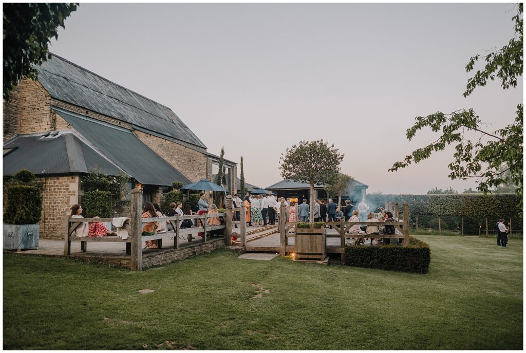 Outside Cripps barn in the evening of a wedding with the fire pits lit