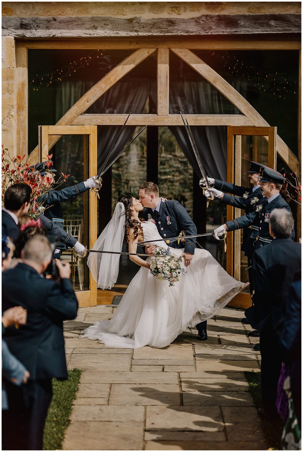 groom giving a drop kiss outside upcote barn during the guard of honour