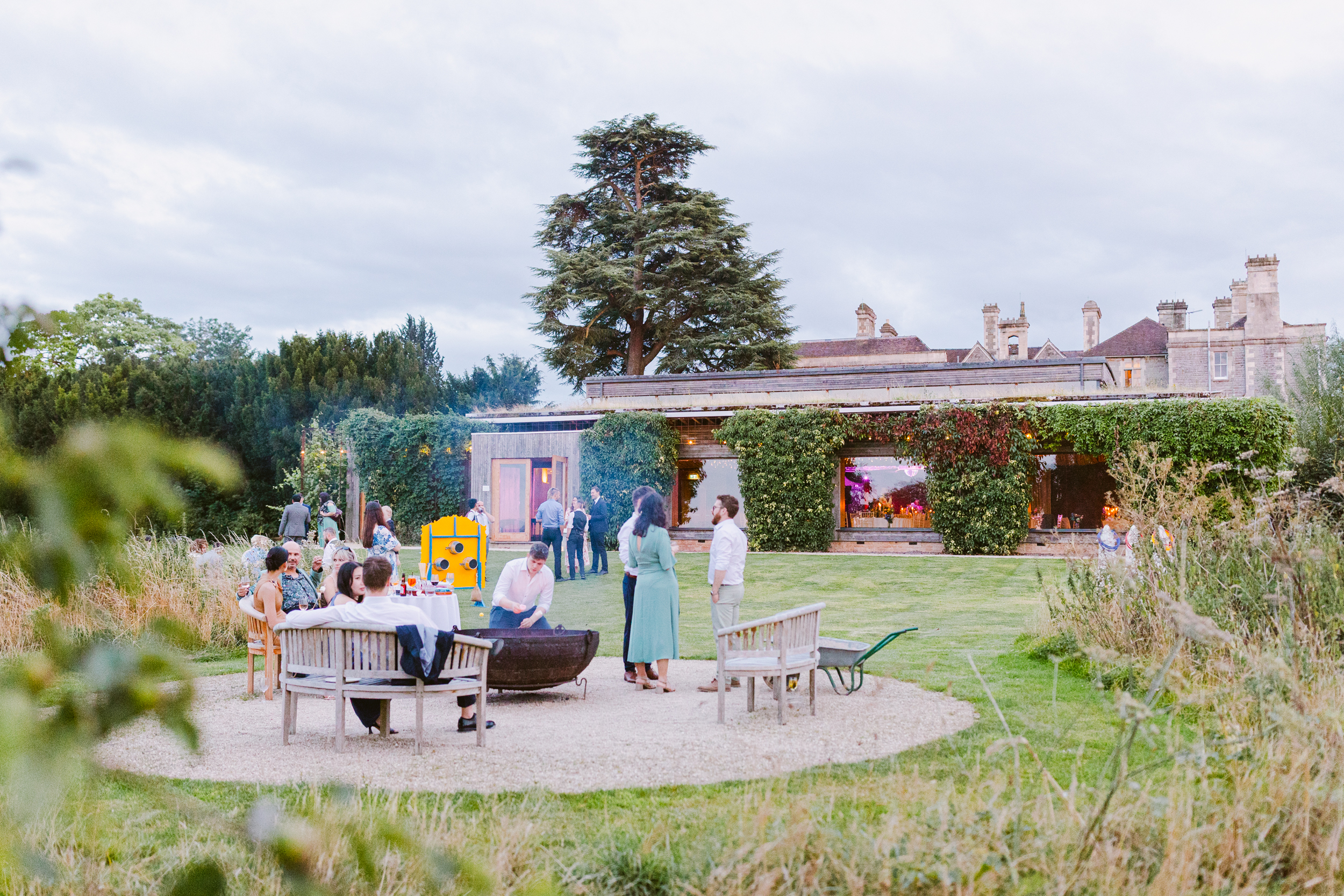 Guests relaxing around the fire pit outside the Gillyflower at an Elmore Court wedding
