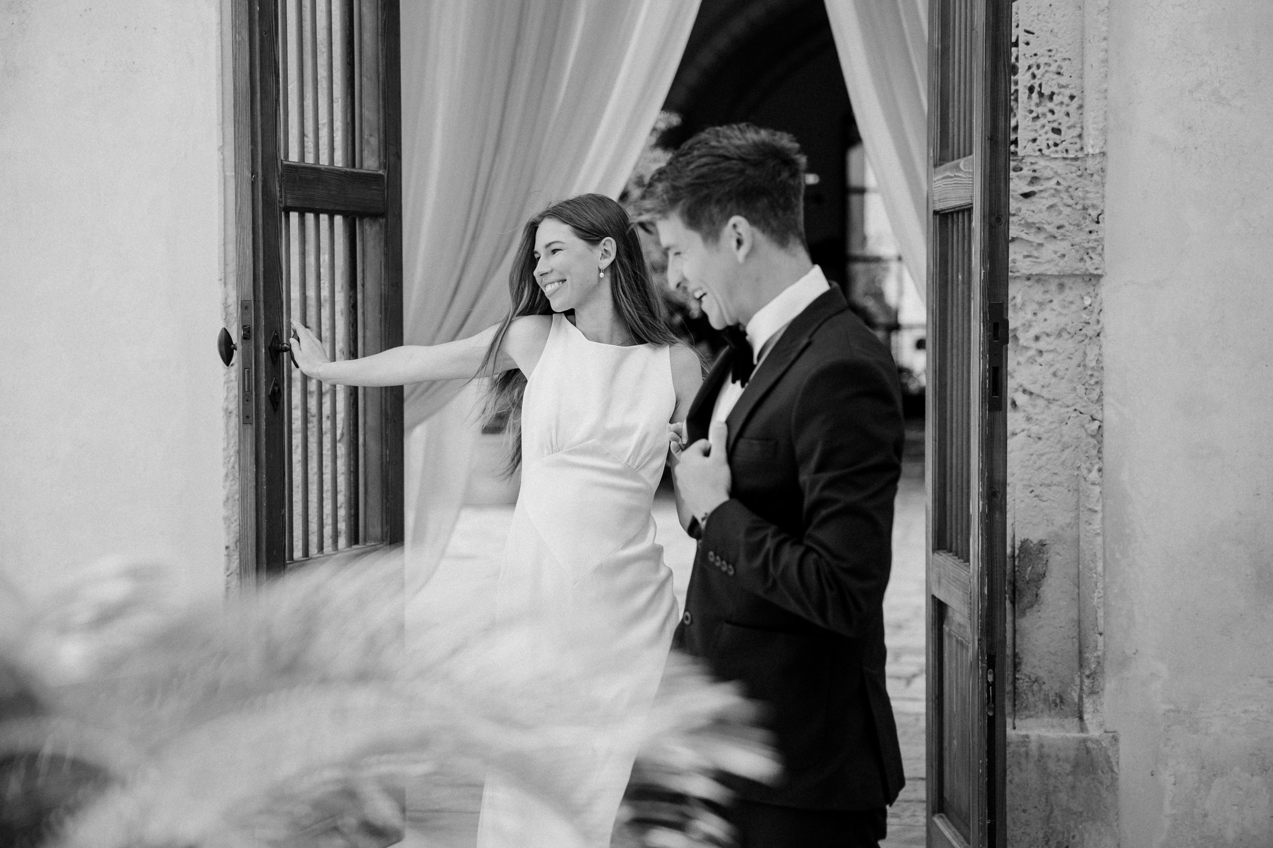 bride and groom having fun and laughing while walking through a door at a puglian wedding
