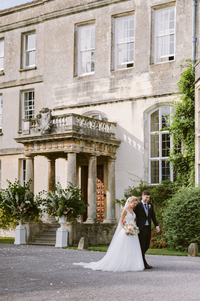 Bride and groom walking hand in hand outside Elmore Court during relaxed wedding portraits