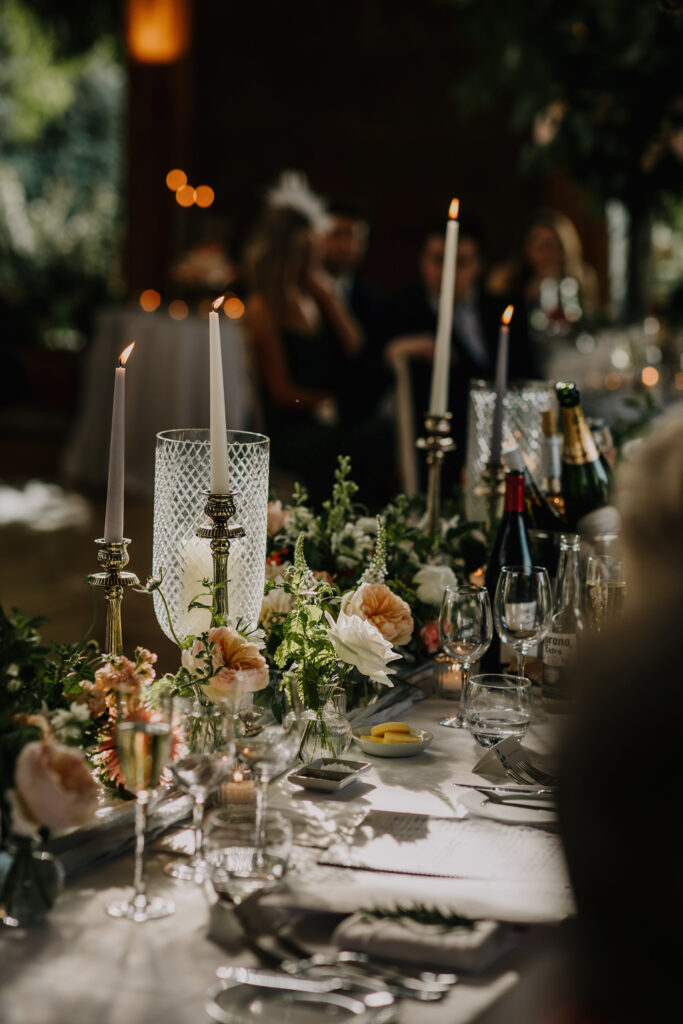 Wedding breakfast table styled with candles, pastel flowers and glassware at Elmore Court’s Gillyflower.