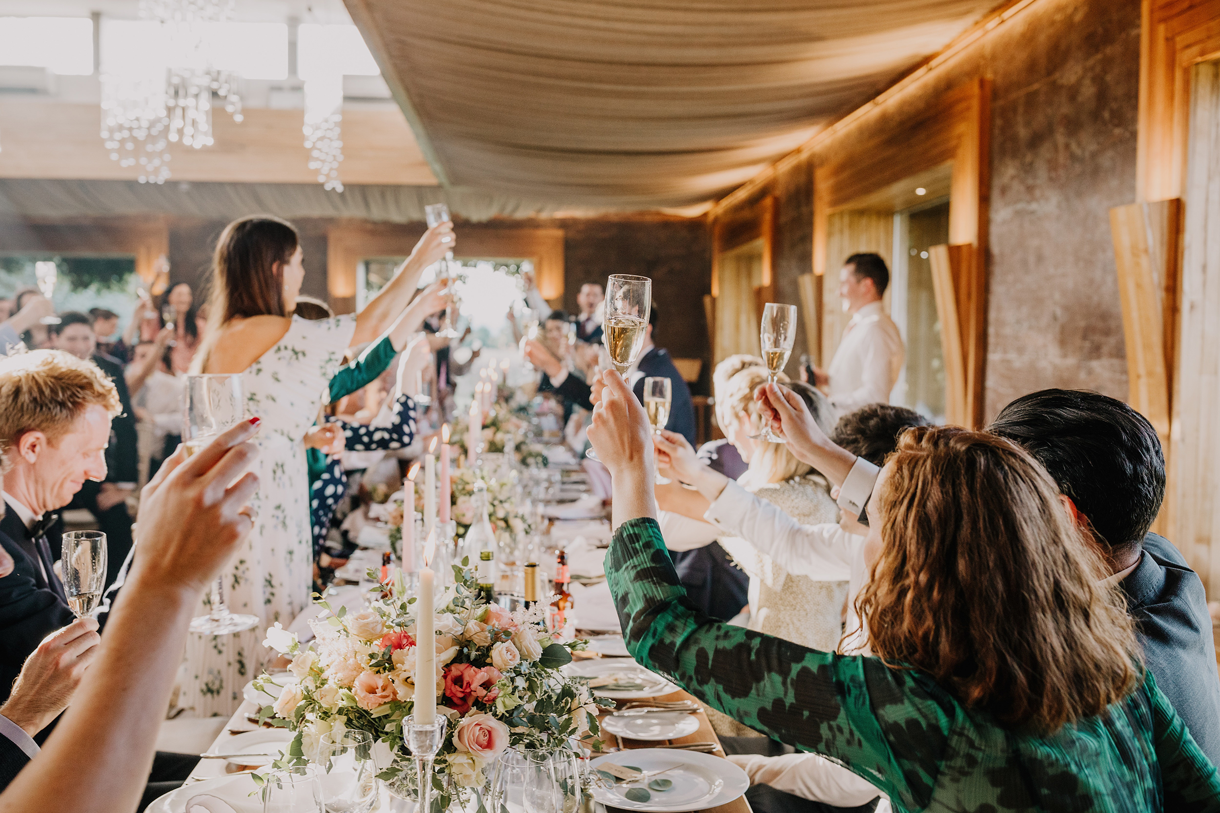 Wedding guests raising glasses during dinner at Elmore Court, enjoying the wedding reception and hospitality

