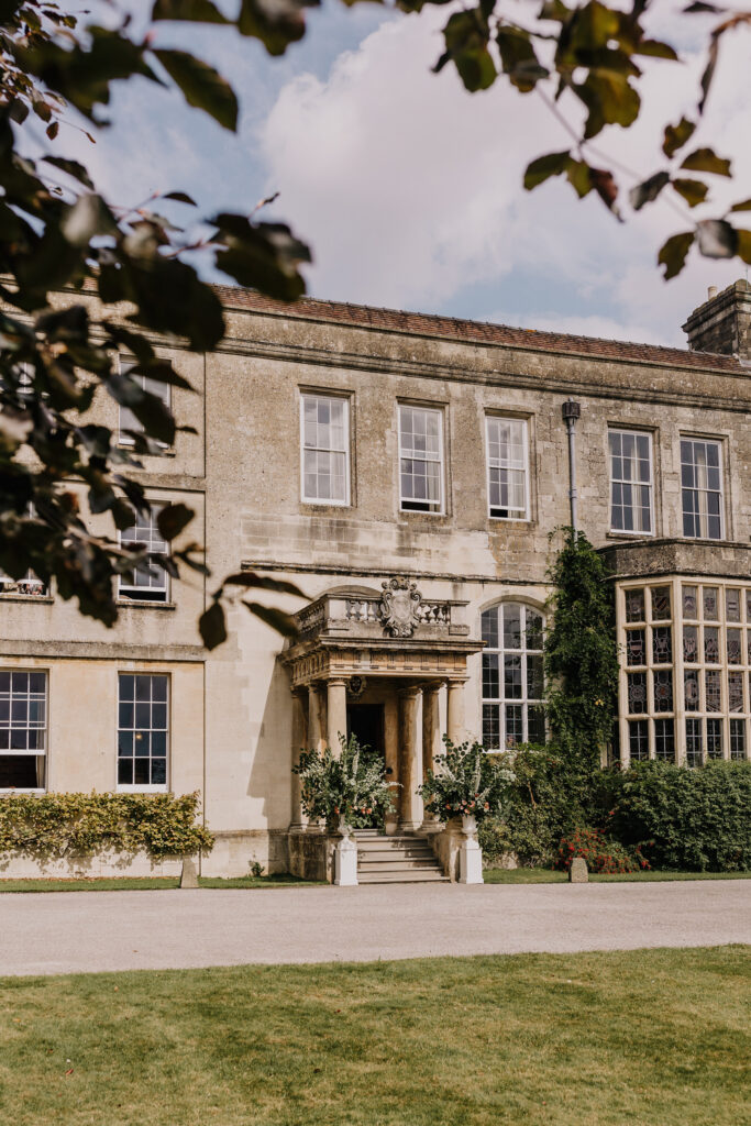 Front entrance of Elmore Court wedding venue with floral arrangements in the Cotswolds. The flowers are by Sorori Design