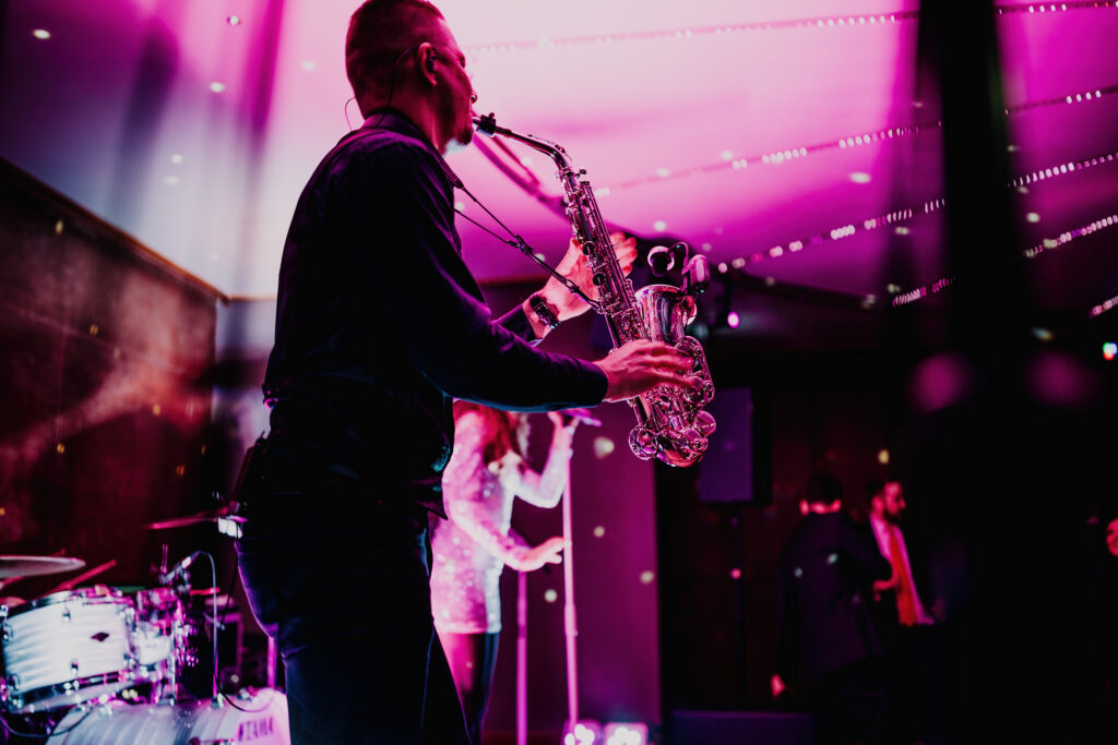 saxophonist playing this saxophone in the gillyflower with purple lighting around him
