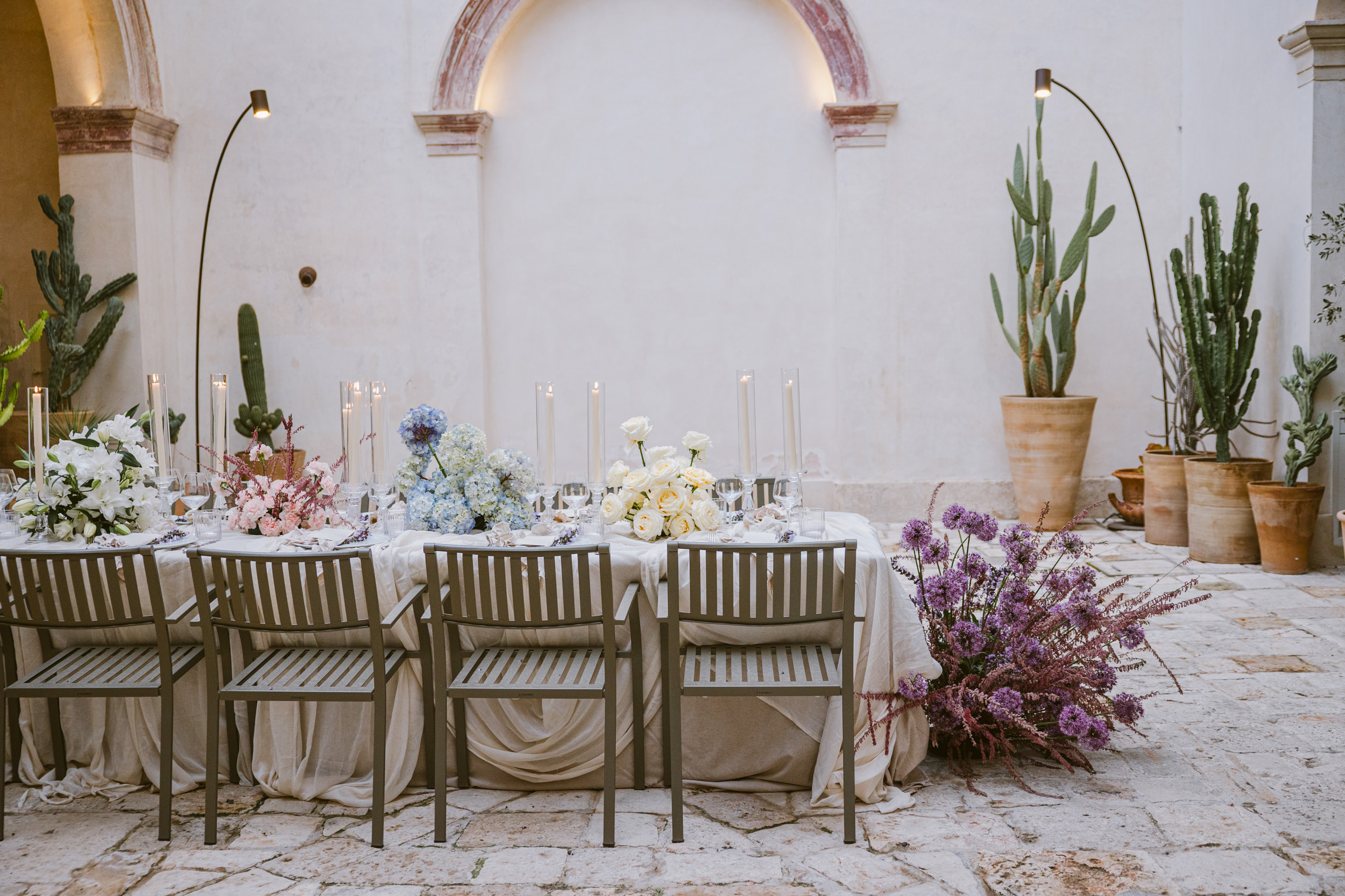 side view of a wedding breakfast table laid up with flowers and candles in a stone courtyard in Puglia