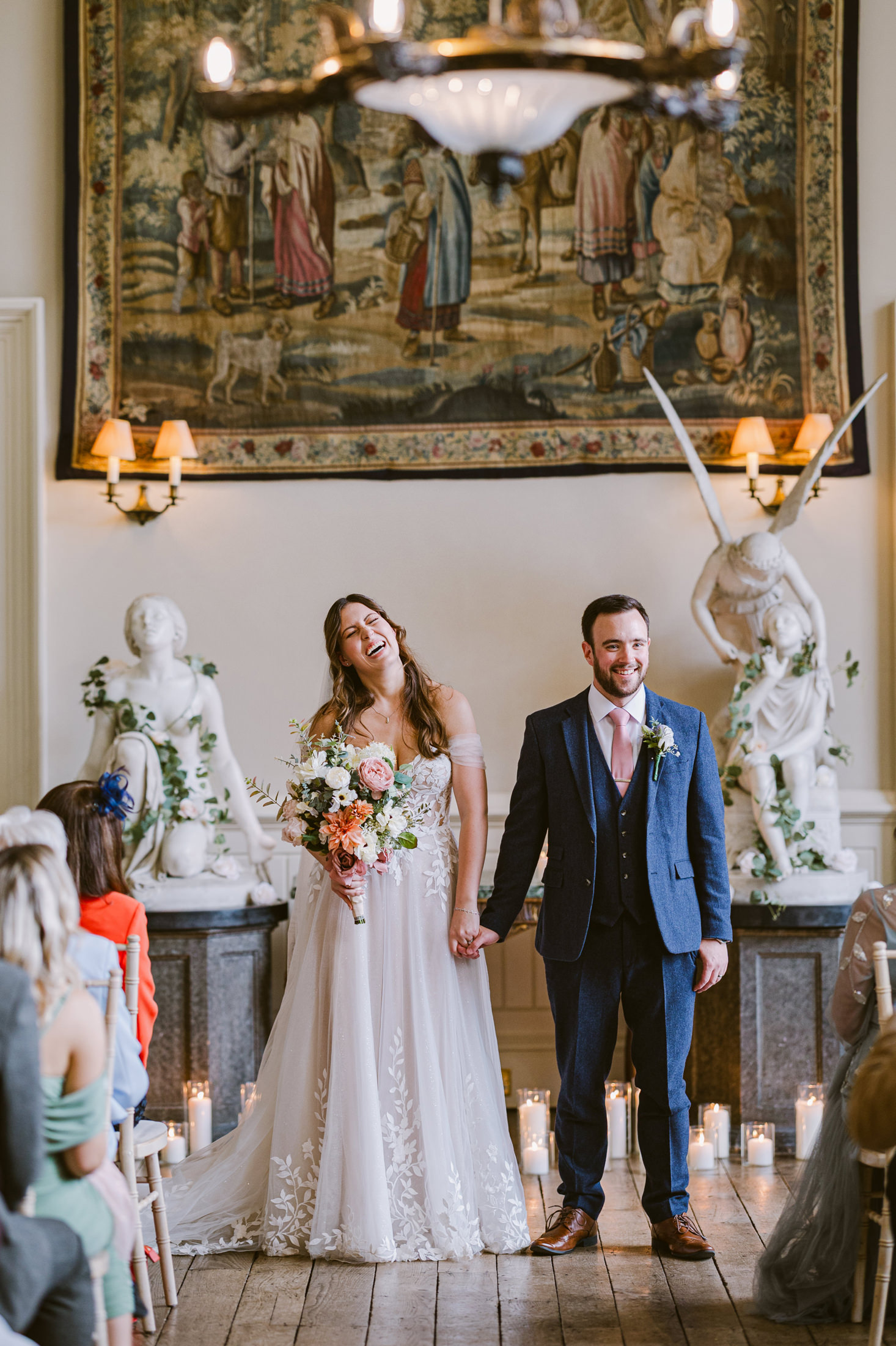 bride laughing and holding groom hand in the Elmore Court main hall 