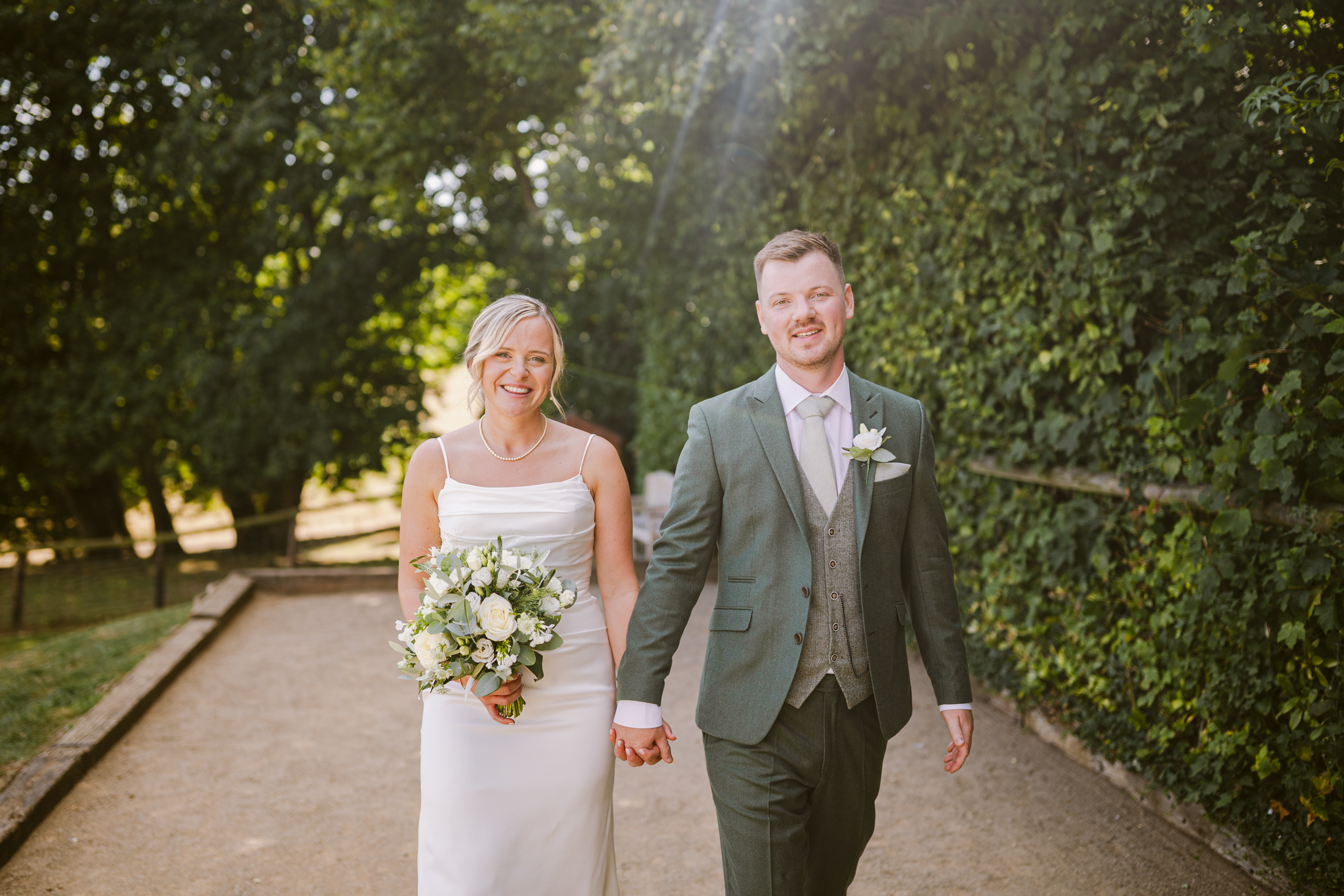 relaxed wedding photo of a couple walking towards camera outside at Kingscote Barn